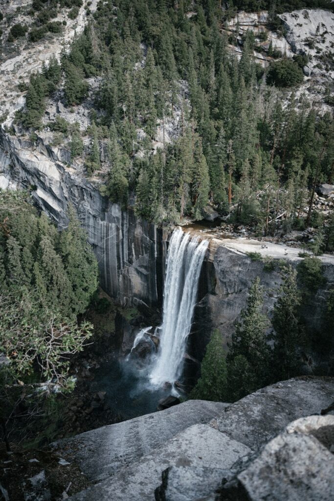 Waterfall cascading down a rocky cliff surrounded by trees