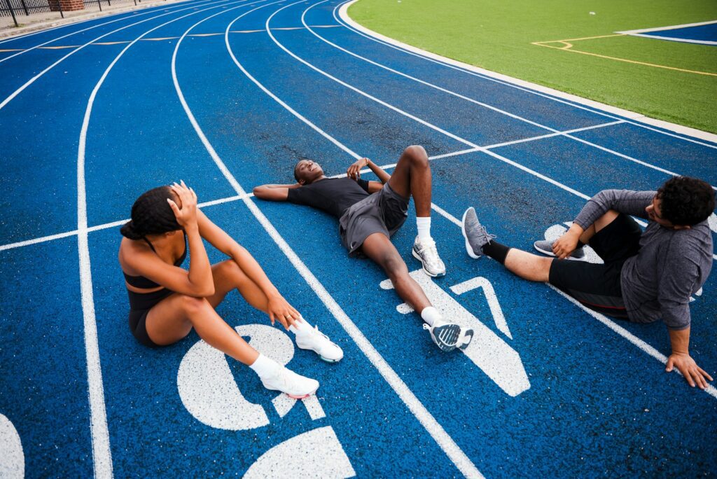 Athletes resting on a blue running track.